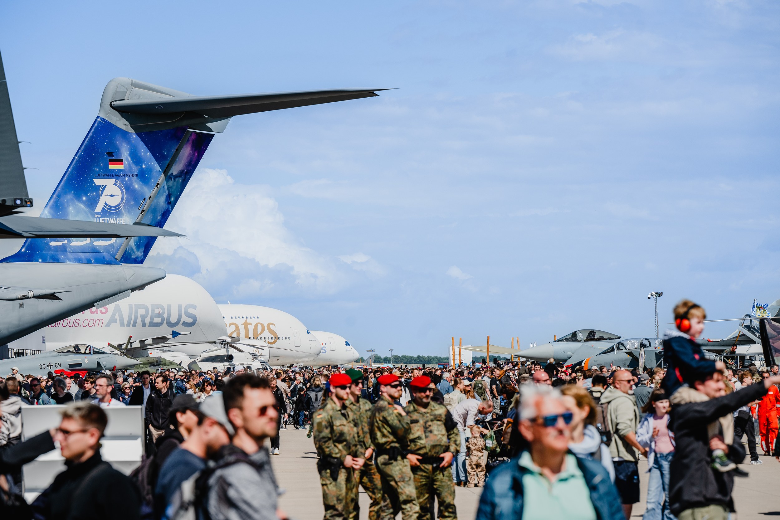 Eine breite Freigeländeansicht zeigt eine dichte Besuchermenge zwischen militärischen und zivilen Fluggeräten im Static …