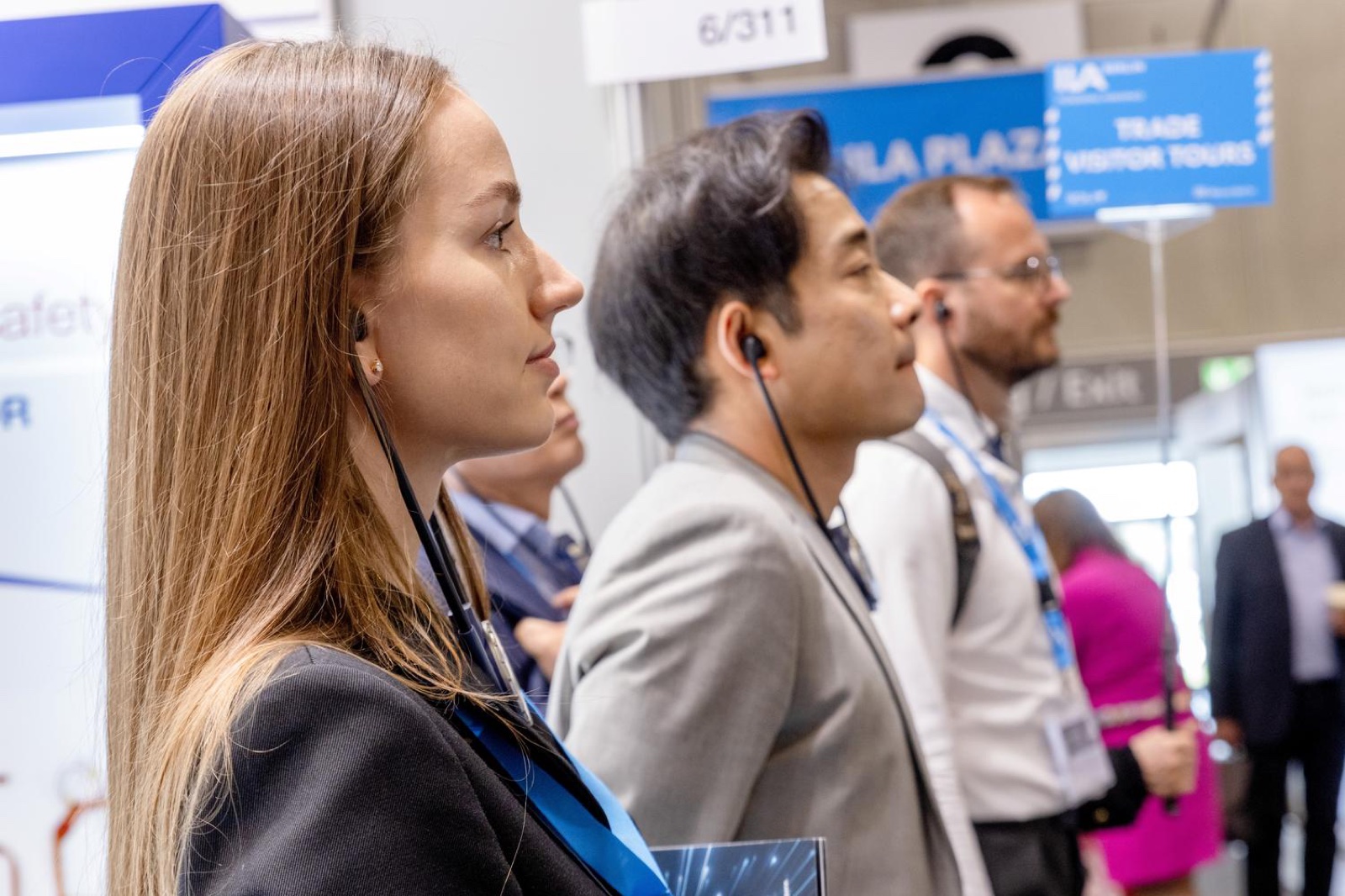 Fachbesucher mit Kopfhörern hören konzentriert zu